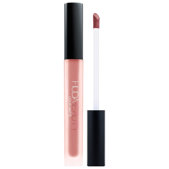 Huda Beauty Liquid Matte Ultra-Comfort Transfer-Proof Lipstick in a sleek tube with swatched color on hand, showcasing matte finish.